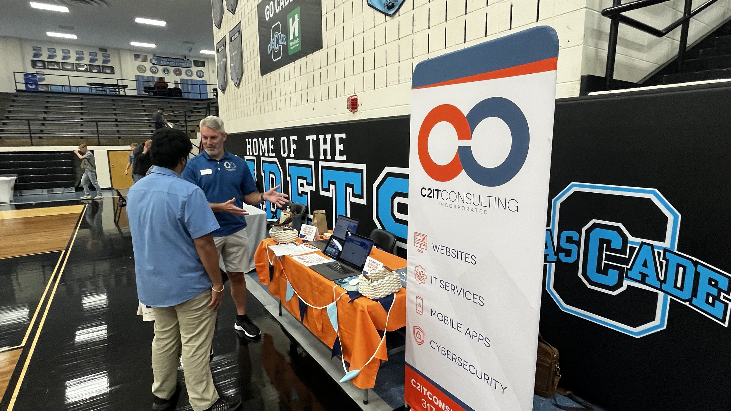 C2IT Consulting is having a conversation with a young student at the C2IT booth during the E3 day at Cascade High School