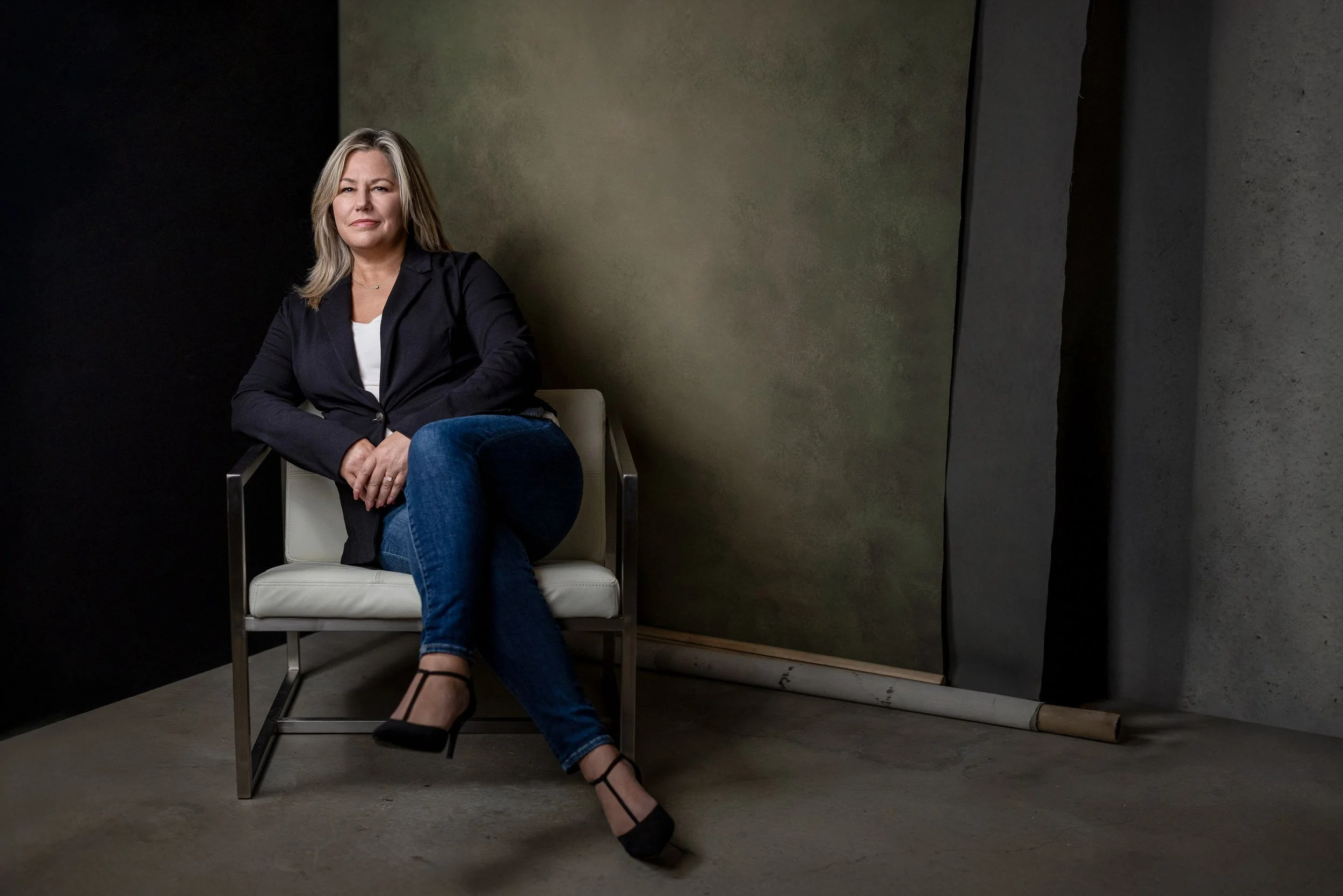 woman sitting on a chair in a studio with a backdrop