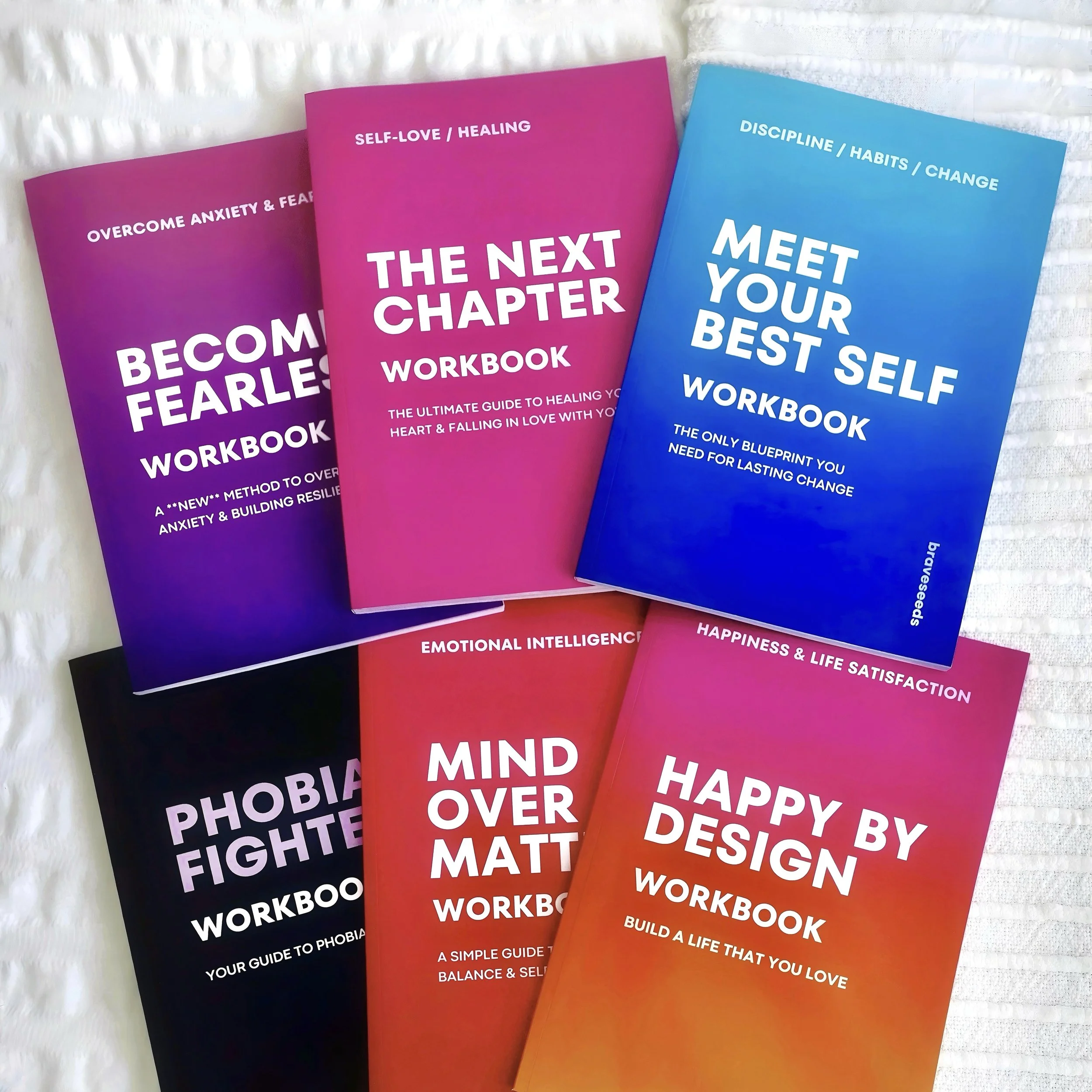 A collection of colorful workbook journals about self-improvement and emotional well-being, titled 'Overcome Anxiety & Fear', 'The Next Chapter', and 'Meet Your Best Self'.