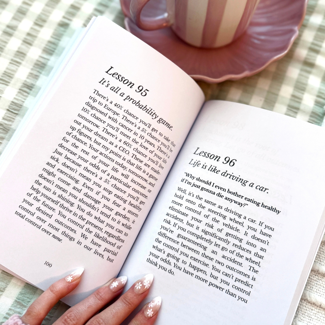 Open book with lessons 95 and 96 about probability and driving a car, on a table with a striped tablecloth, a pink dish, and a striped mug.