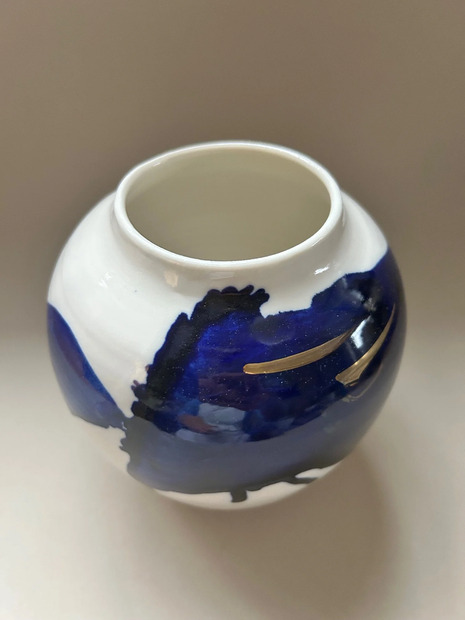Close-up of a ceramic vase with a white and dark blue painted design, viewed from above.
