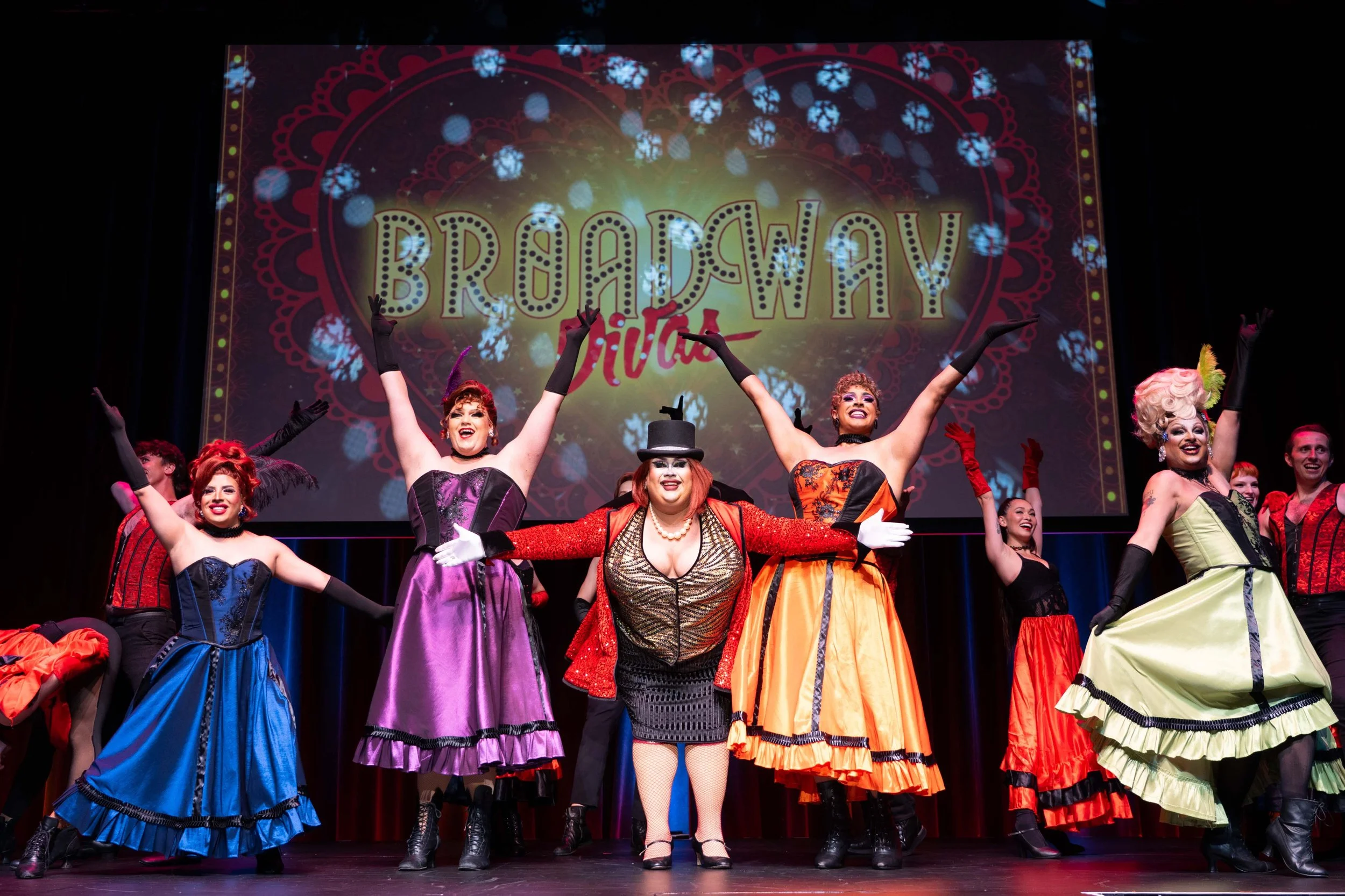 Performers on stage at Broadway Viva show, dressed in colorful costumes with a large backdrop reading 'Broadway Divas'. Miss Clair Voyance Broadway Divas SCFTA