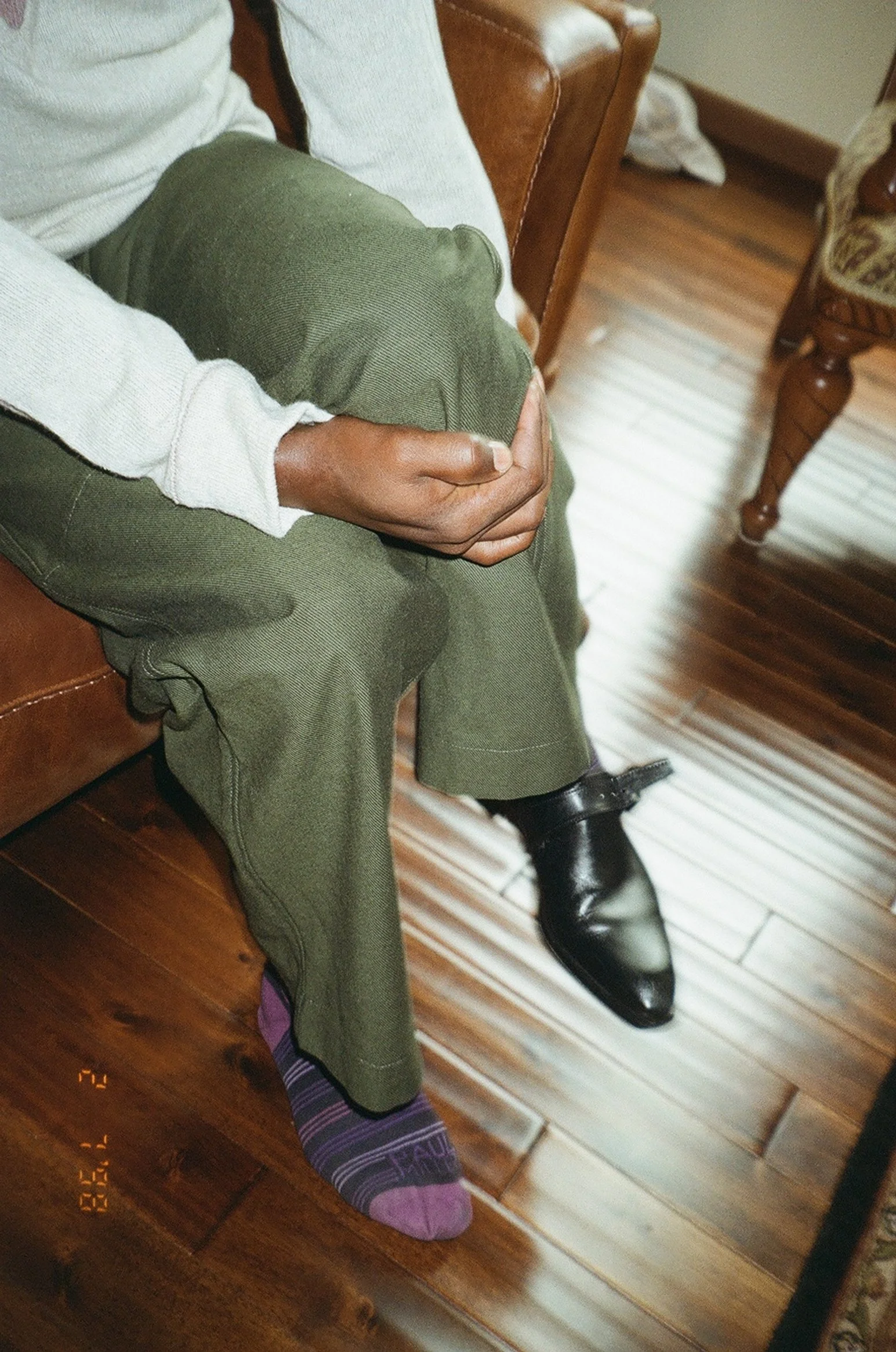 A closeup image of a mans legs adjusting his dress shoes.