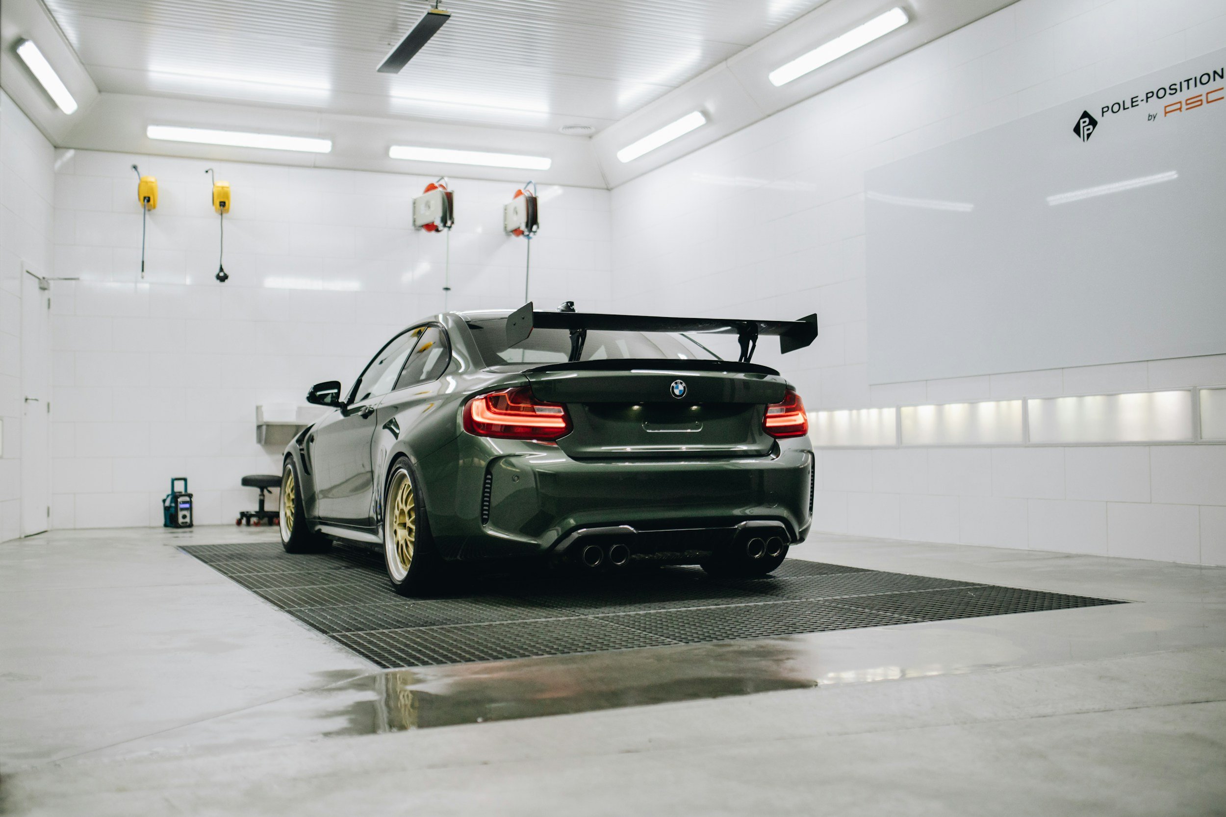 BMW car with a large rear spoiler in a clean garage setting