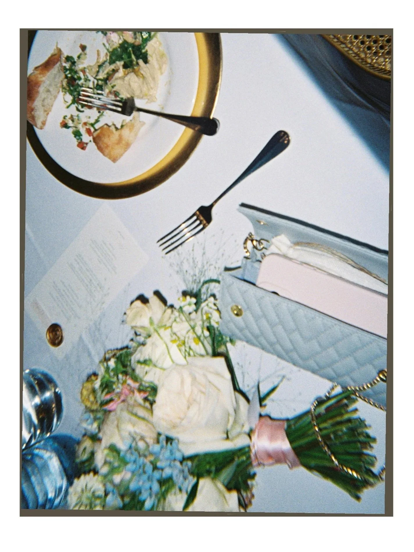 Ein Tisch mit Blumenstrauß und tellern mit Salat, Wasserflaschen, Brot und Besteck.