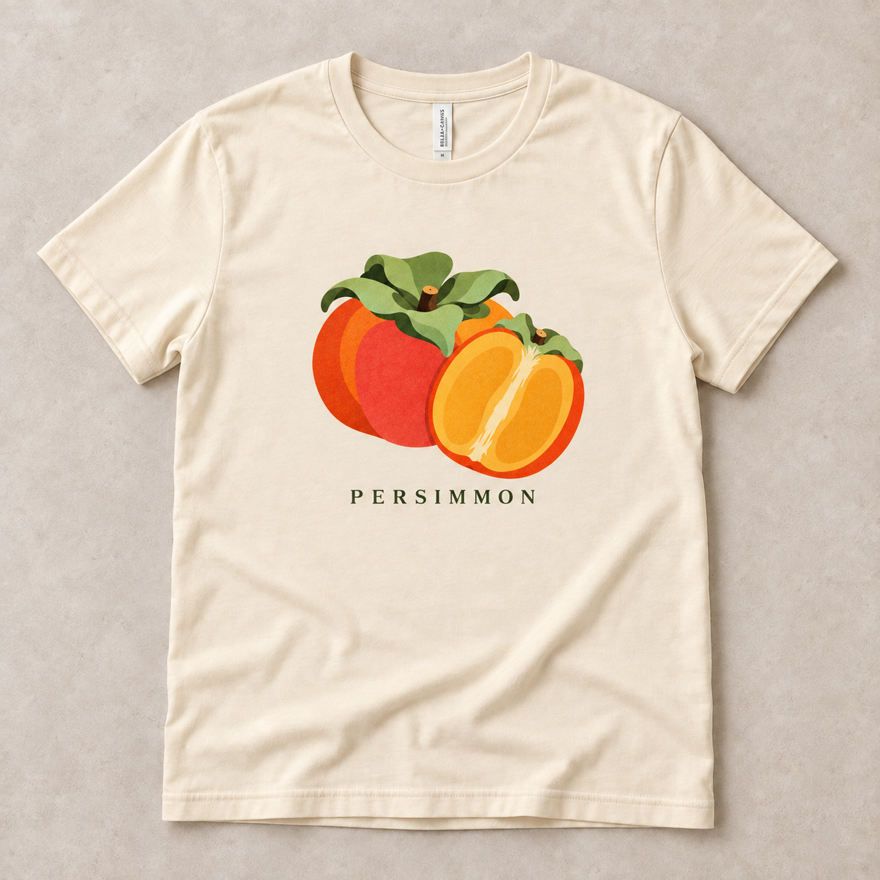 Natural Persimmon T-shirt with a whole orange persimmon, a golden cut half and green leaves printed on the front.