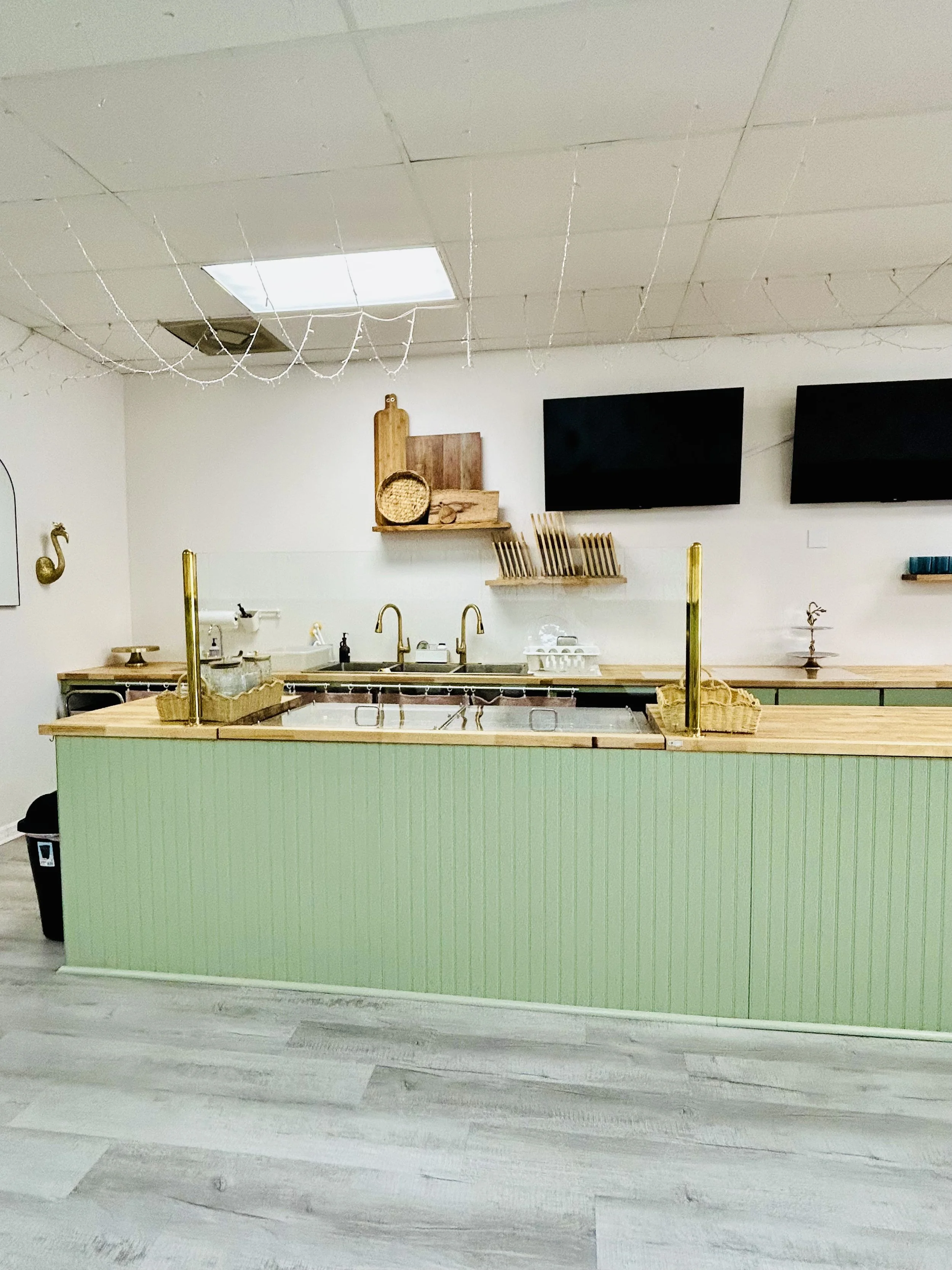 Build your own charcuterie board station with beautiful cutting boards in background, two televisions, butcher block counter top, mint counter base