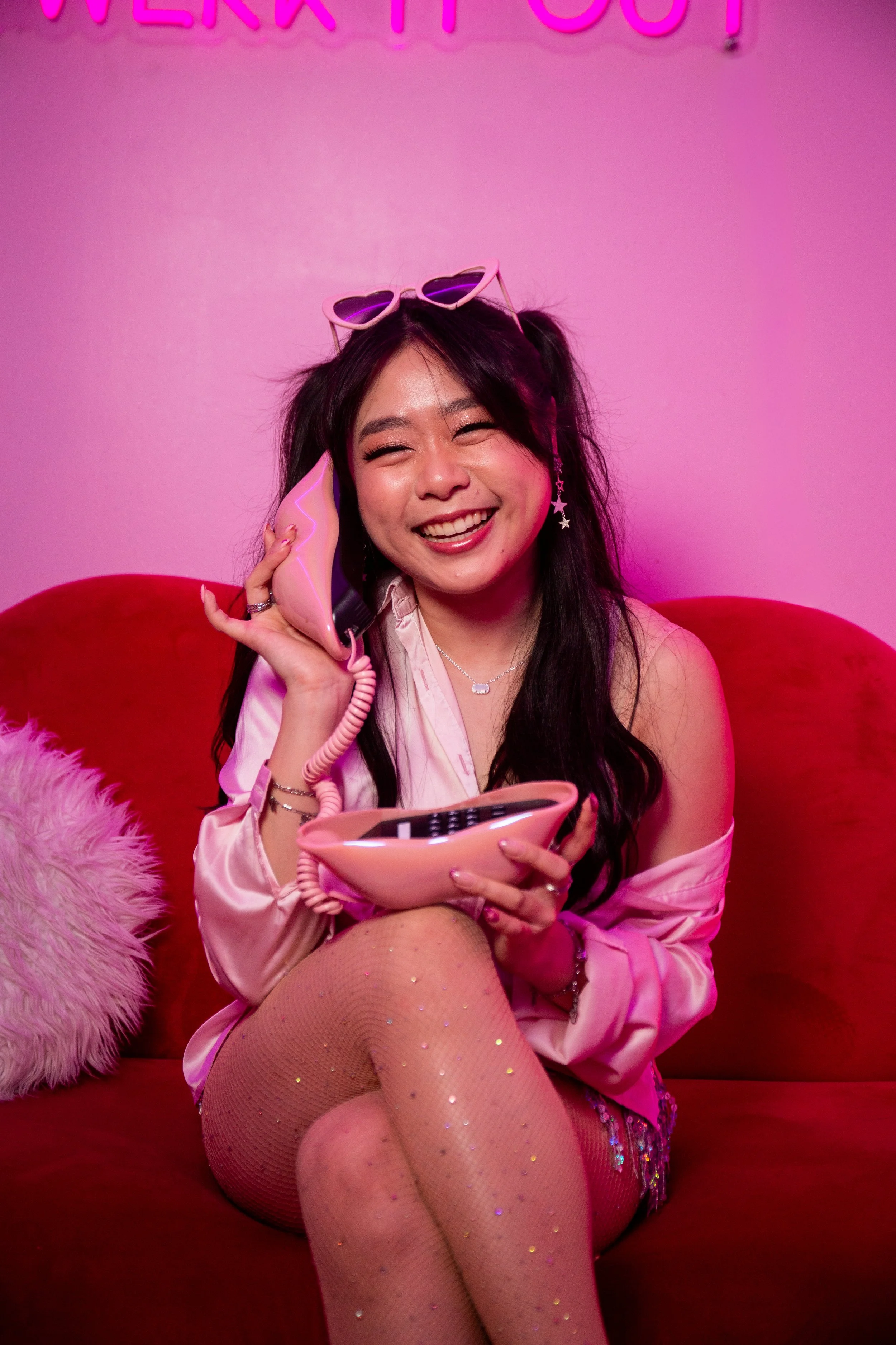 a young woman smiling on the phone on the couch in y2k pink decor