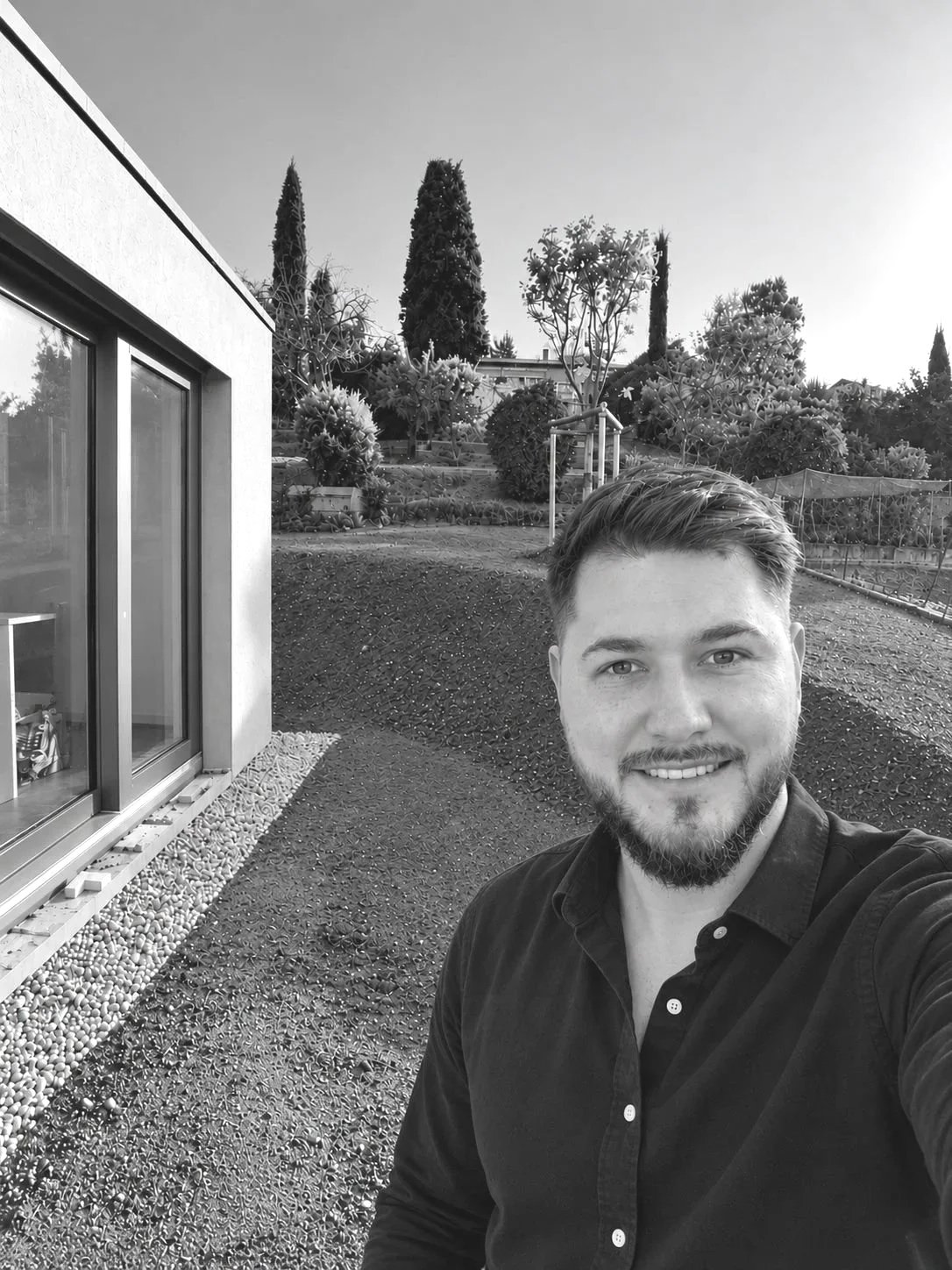 Selfie d'un homme souriant dans un jardin avec des plantes et des arbres
