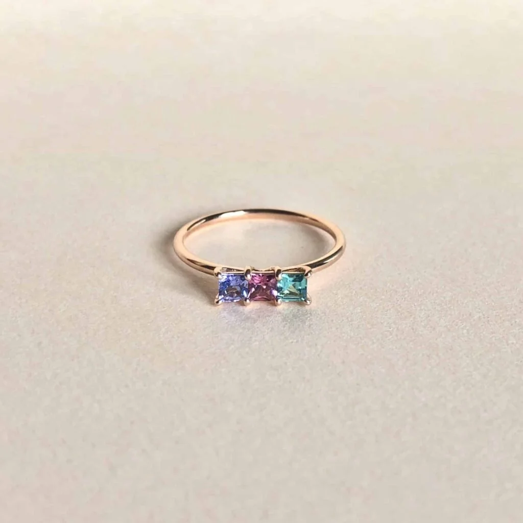 Bague en or avec trois pierres précieuses carrées de couleurs différentes.