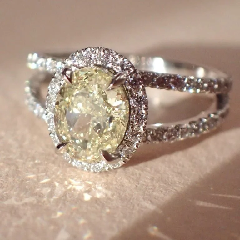 Bague en diamant jaune avec halo de diamants blancs sur un fond flou.
