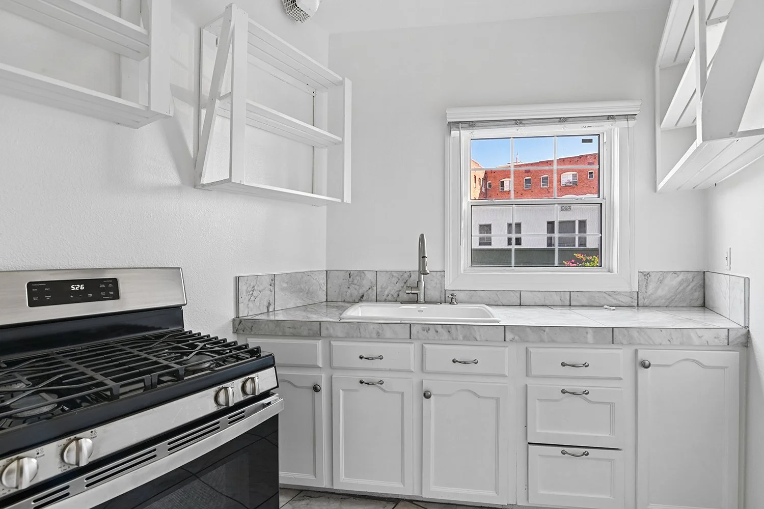 Kitchen in Cahuenga apartment home with tile flooring and a charming window allowing for gorgeous natural lighting. plenty of cabinet space. 