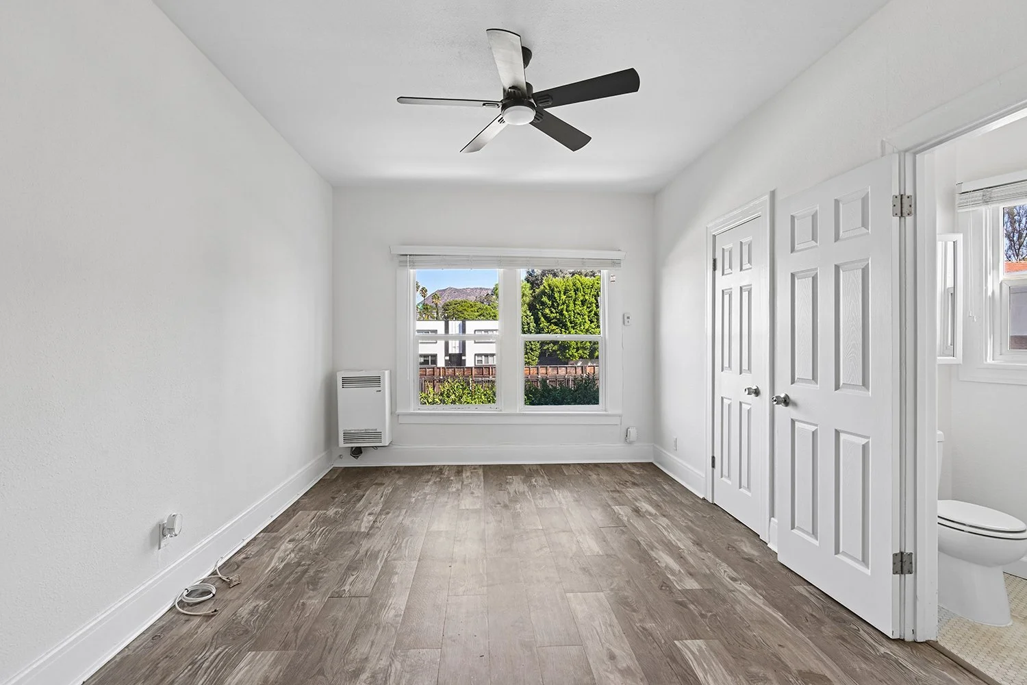 Interior of Cahuenga apartment home with wood flooring, ceiling fan, charming windows and architectural details, and gorgeous natural lighting filtering throughout the space. This is a classic old-hollywood apartment 