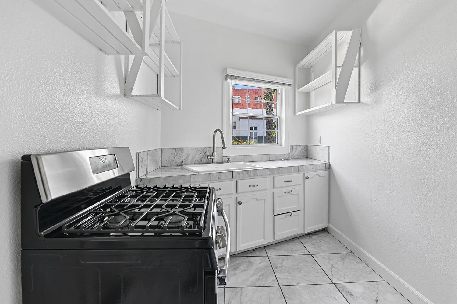 Kitchen in Cahuenga apartment home with tile flooring and a charming window allowing for gorgeous natural lighting. plenty of cabinet space. 