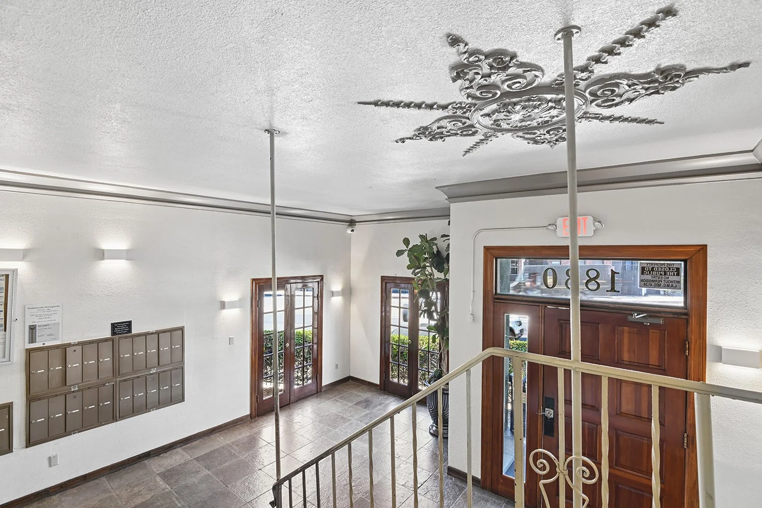 Lobby in Cahuenga apartments with unique architectural details, wood entry door, plants, and charming staircase. 