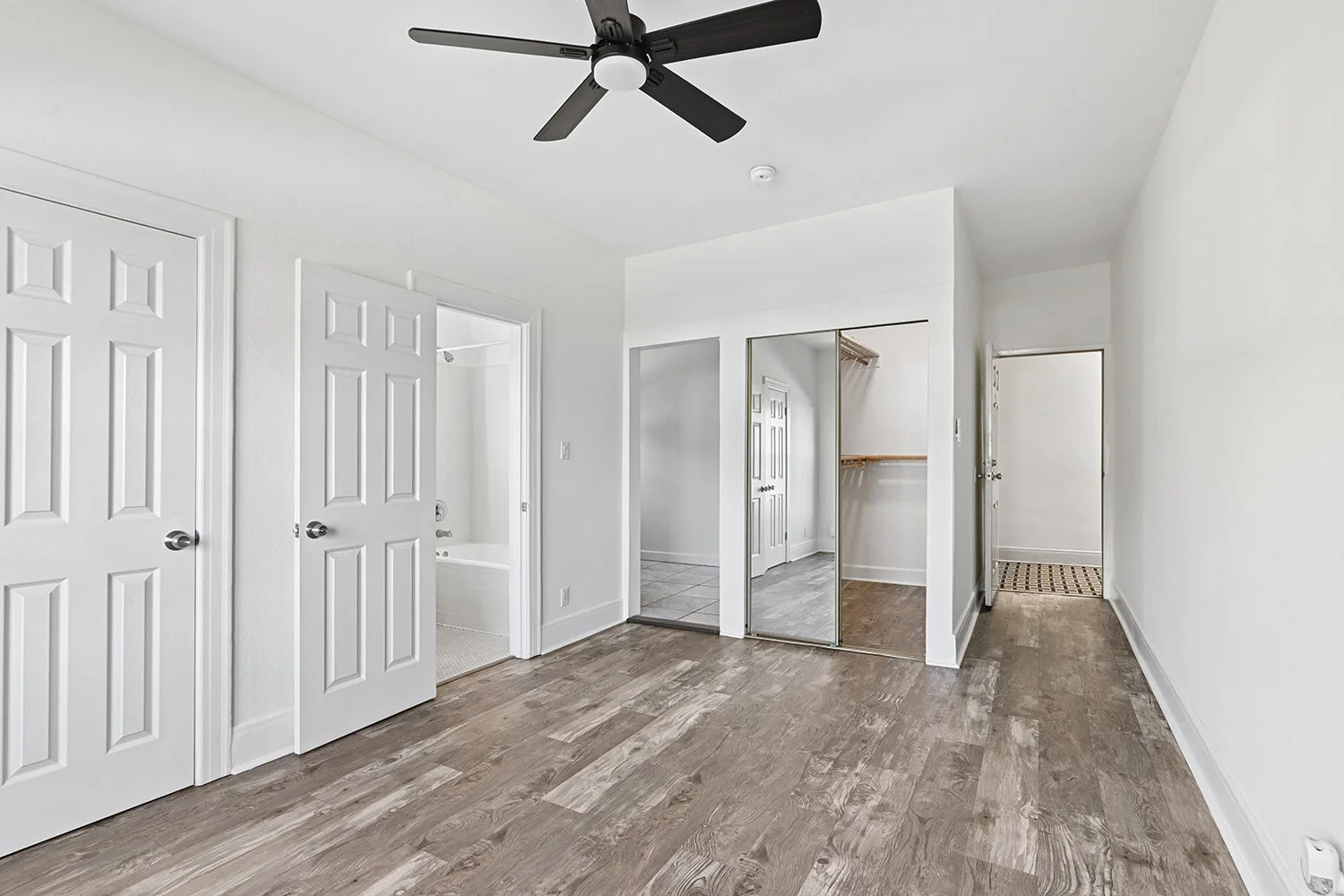 Interior of Cahuenga apartment home with wood flooring, ceiling fan, charming windows and architectural details, and gorgeous natural lighting filtering throughout the space. This is a classic old-hollywood apartment 