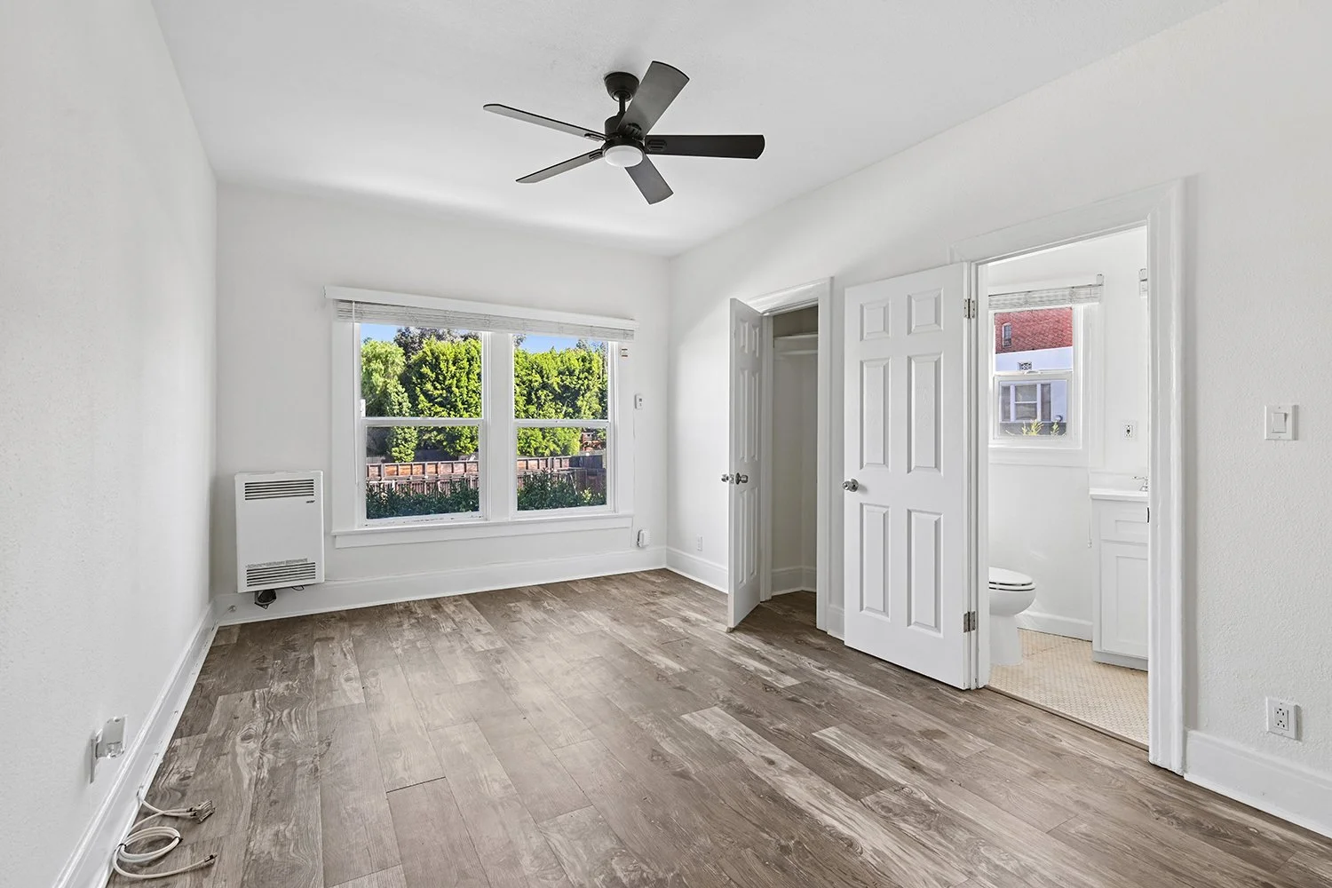 Interior of Cahuenga apartment home with wood flooring, ceiling fan, charming windows and architectural details, and gorgeous natural lighting filtering throughout the space. This is a classic old-hollywood apartment 