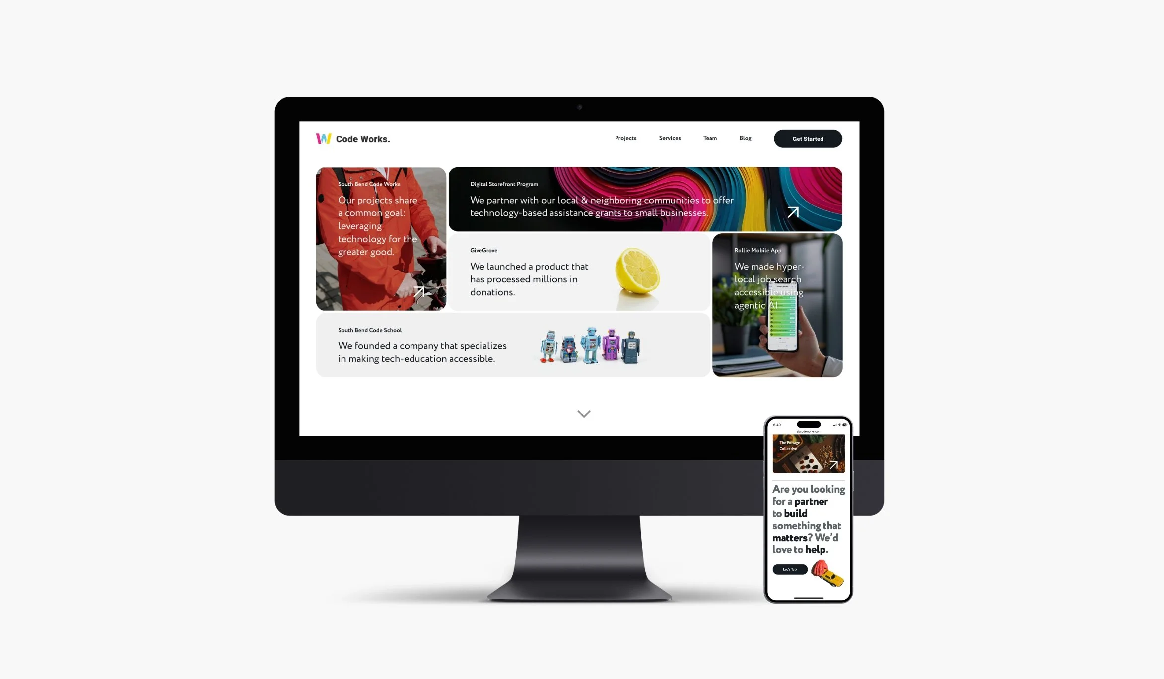 A computer monitor and smartphone display a website for 'Code Works', showing projects, services, team, blog, and a 'Get Started' button with colorful graphics, text, images of a person using a phone, lemon, robots, and various colorful artwork.