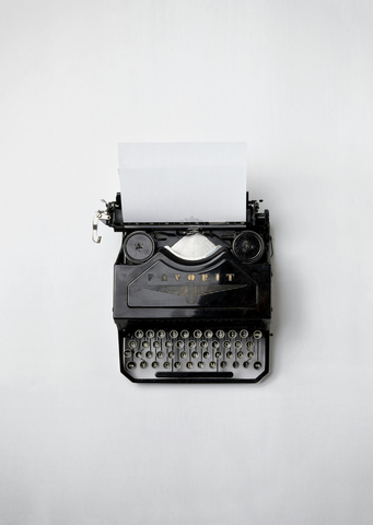 Vintage black typewriter with paper on a white background