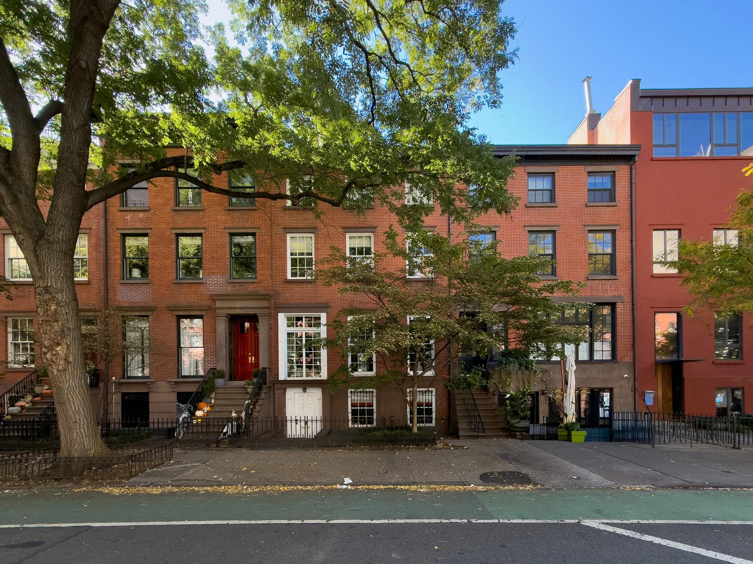 Brick townhouses along a tree-lined street in the West Village, Manhattan, NYC, highlighting the neighborhood’s residential architecture and real estate character.
