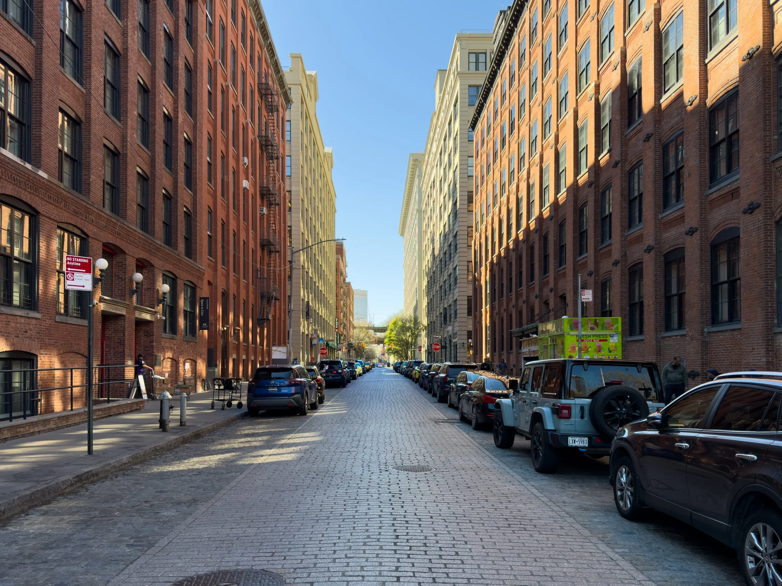 Cobblestone street lined with historic industrial buildings in DUMBO, Brooklyn, NYC, highlighting the neighborhood’s residential streetscape and adaptive reuse architecture.