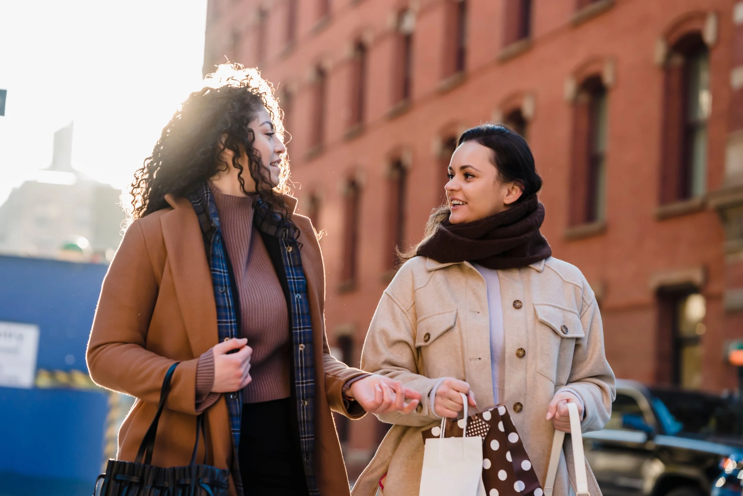 Two people walking along a mixed-use New York City street, illustrating how retail, walkability, public space, and neighborhood amenities shape residential demand in NYC real estate.