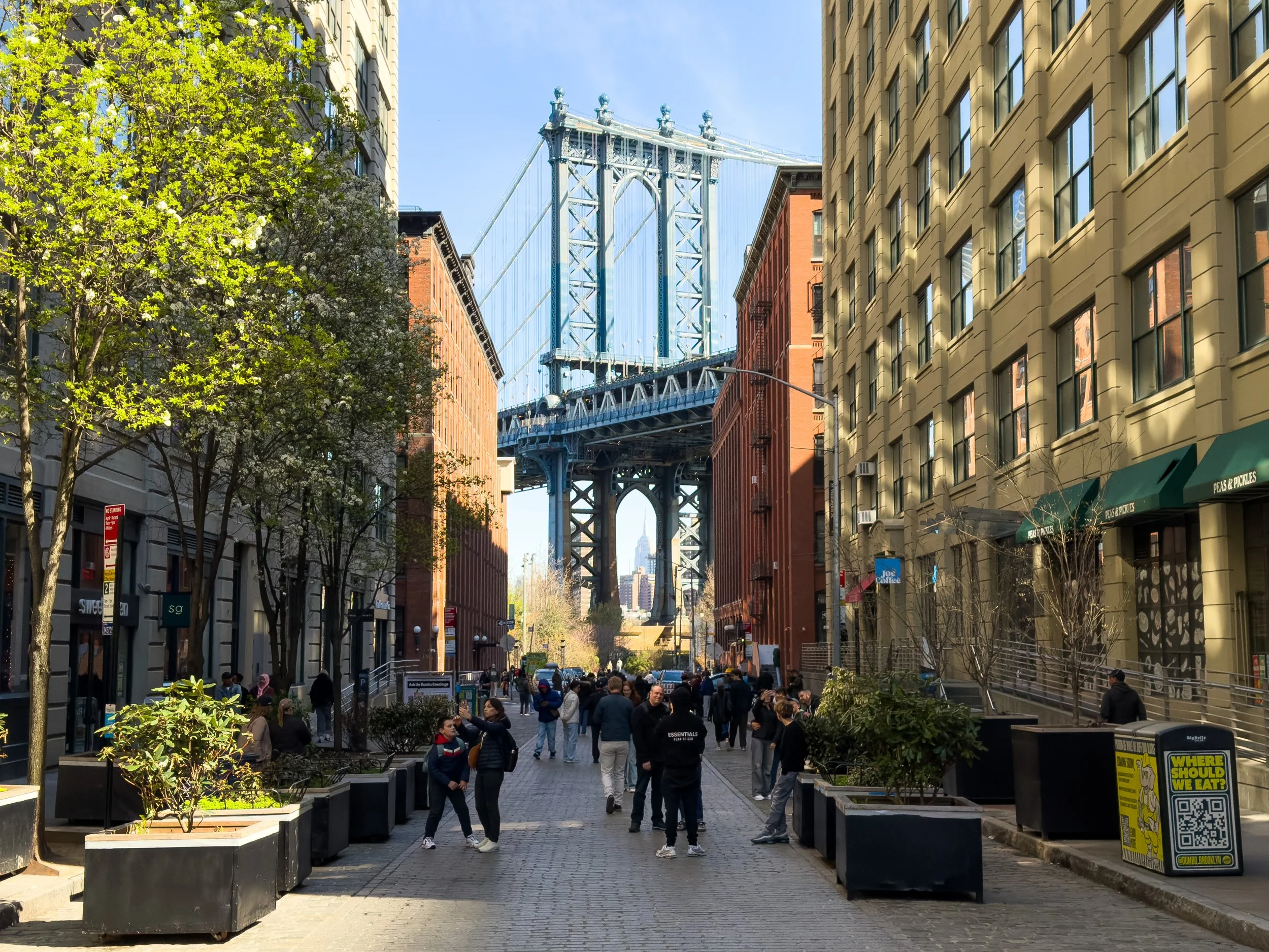 View of the Manhattan Bridge along a cobblestone street in DUMBO, Brooklyn, New York, NYC, highlighting the neighborhood’s historic streetscape and surrounding residential buildings.