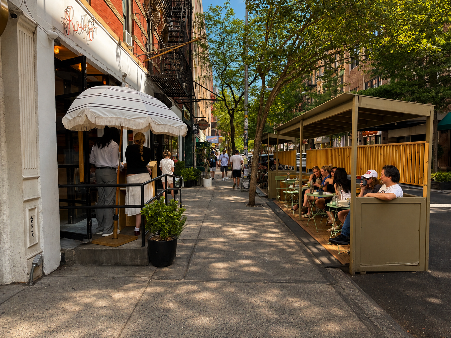 Outdoor café seating on a tree-lined Nolita sidewalk in Manhattan.