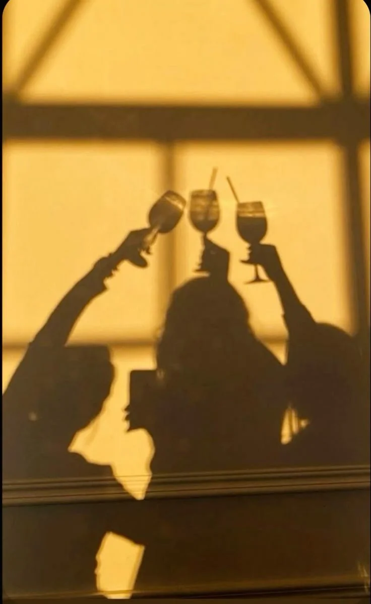 Shadow of friends holding up wine glasses