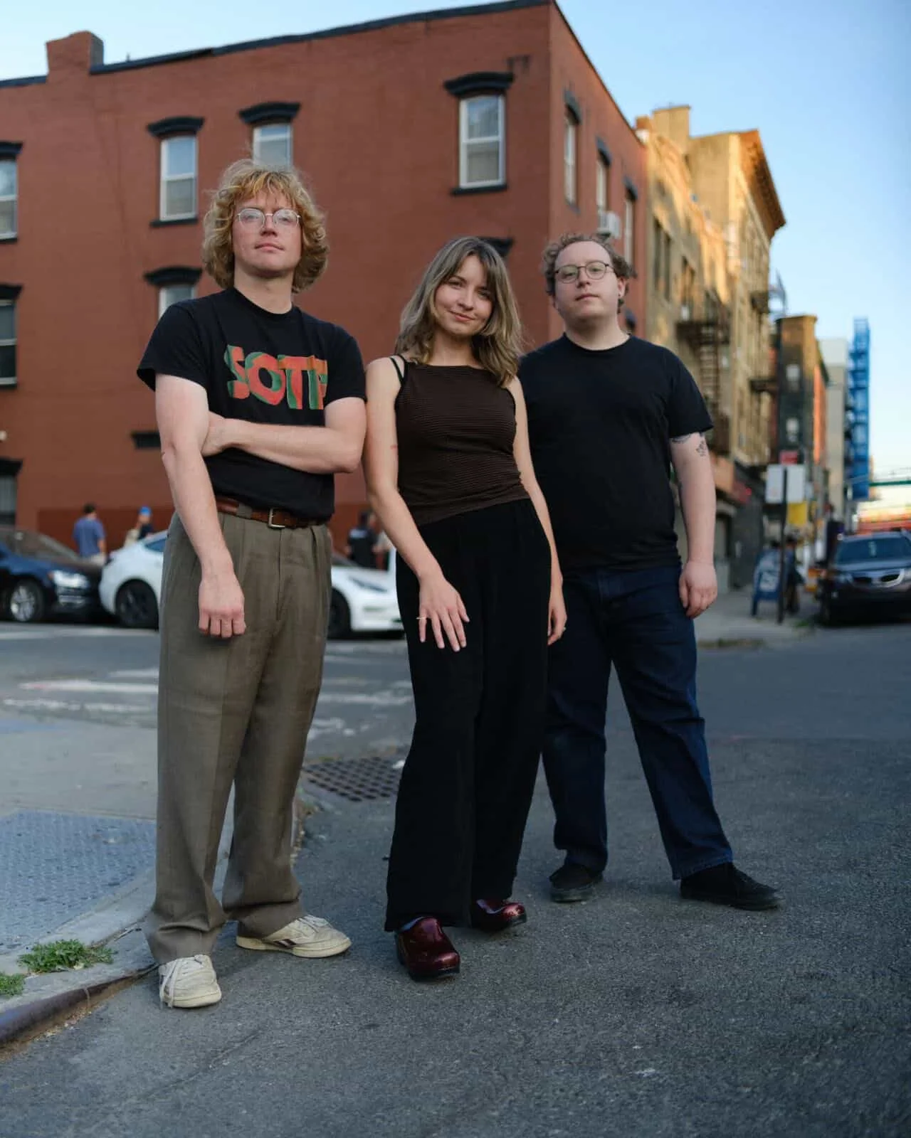 Why Bonnie band members Blair Howerton, Chance Williams, and Josh Malett standing on a street corner in Brooklyn, New York, in front of a red brick building.