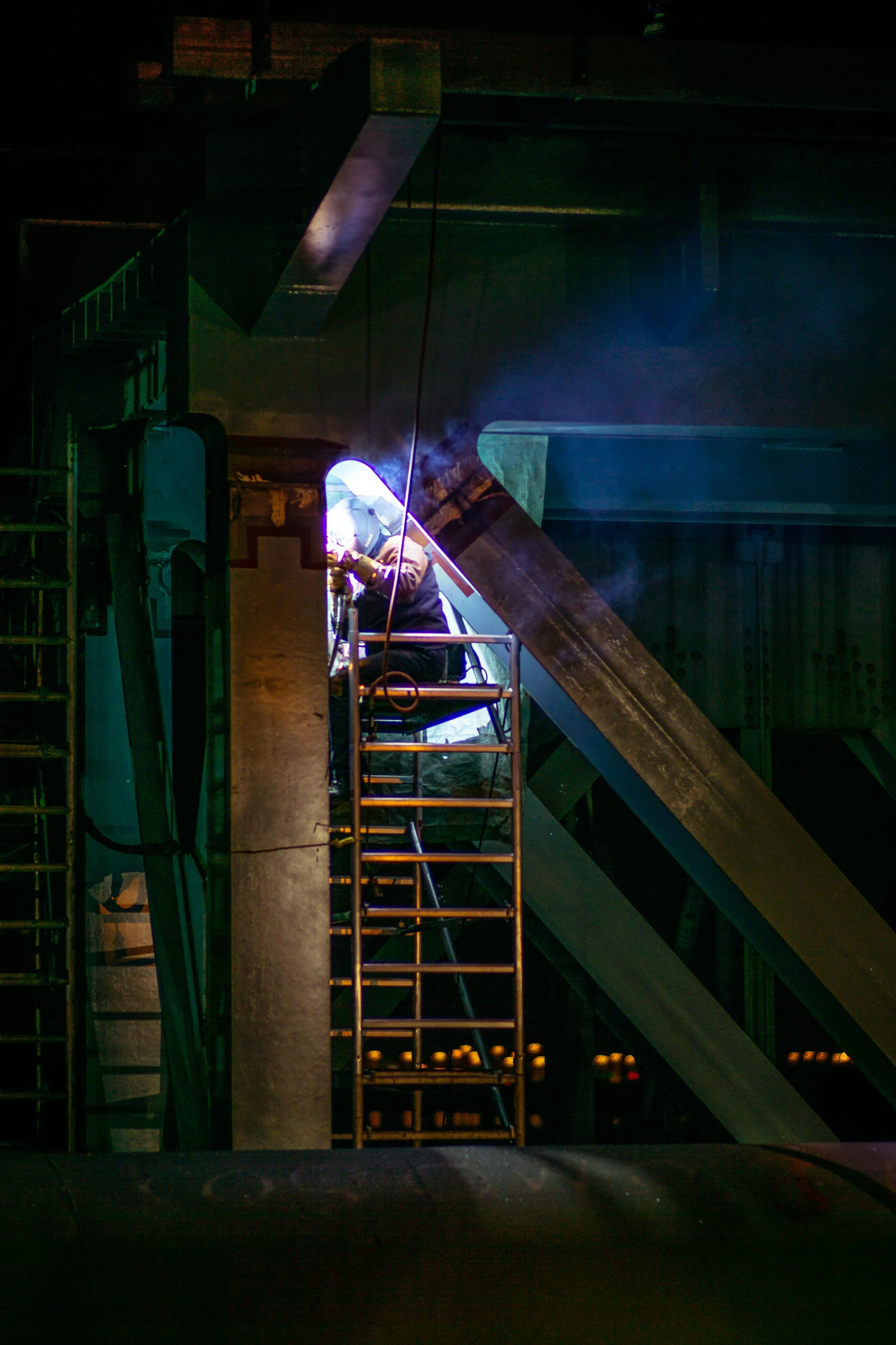 Construction site with orange boom lift, solar panel installation, scaffolding, parked cars, blue sky background.Steel erection.