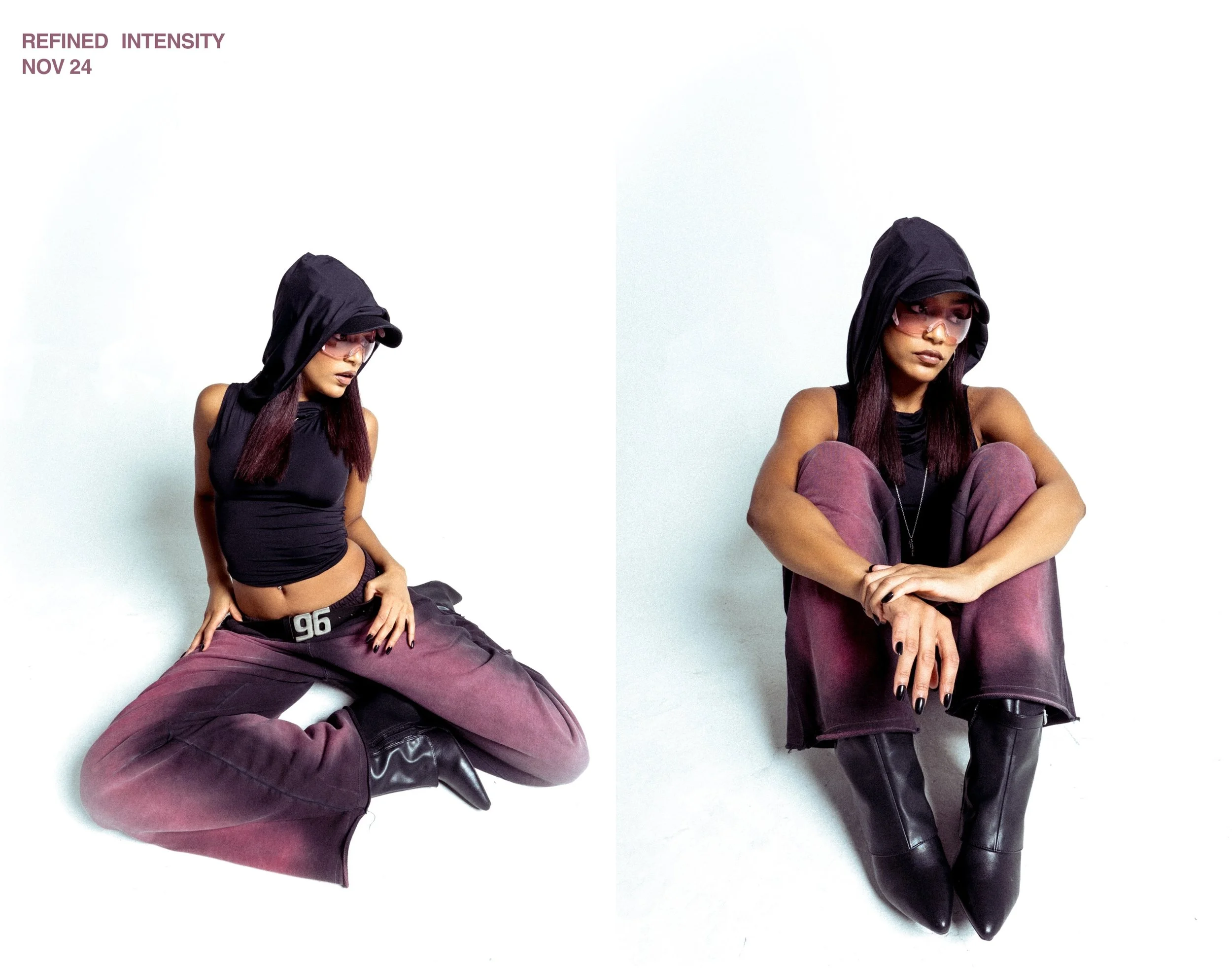 Two young women with dark hair wearing black hoodies, sunglasses, and purple pants, sitting against a plain white background. The woman on the left is in a crouched position with one hand on her knee and another on the ground, while the woman on the 