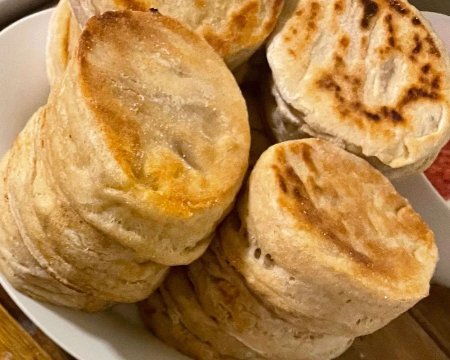 A white bowl filled with cooked, rolled tortillas that are golden brown and slightly crispy on the edges.