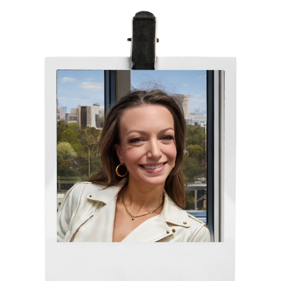 Portrait of a beautiful smiling woman with brown hair, wearing hoop earrings and a white jacket, in front of a window with cityscape and trees outside.
