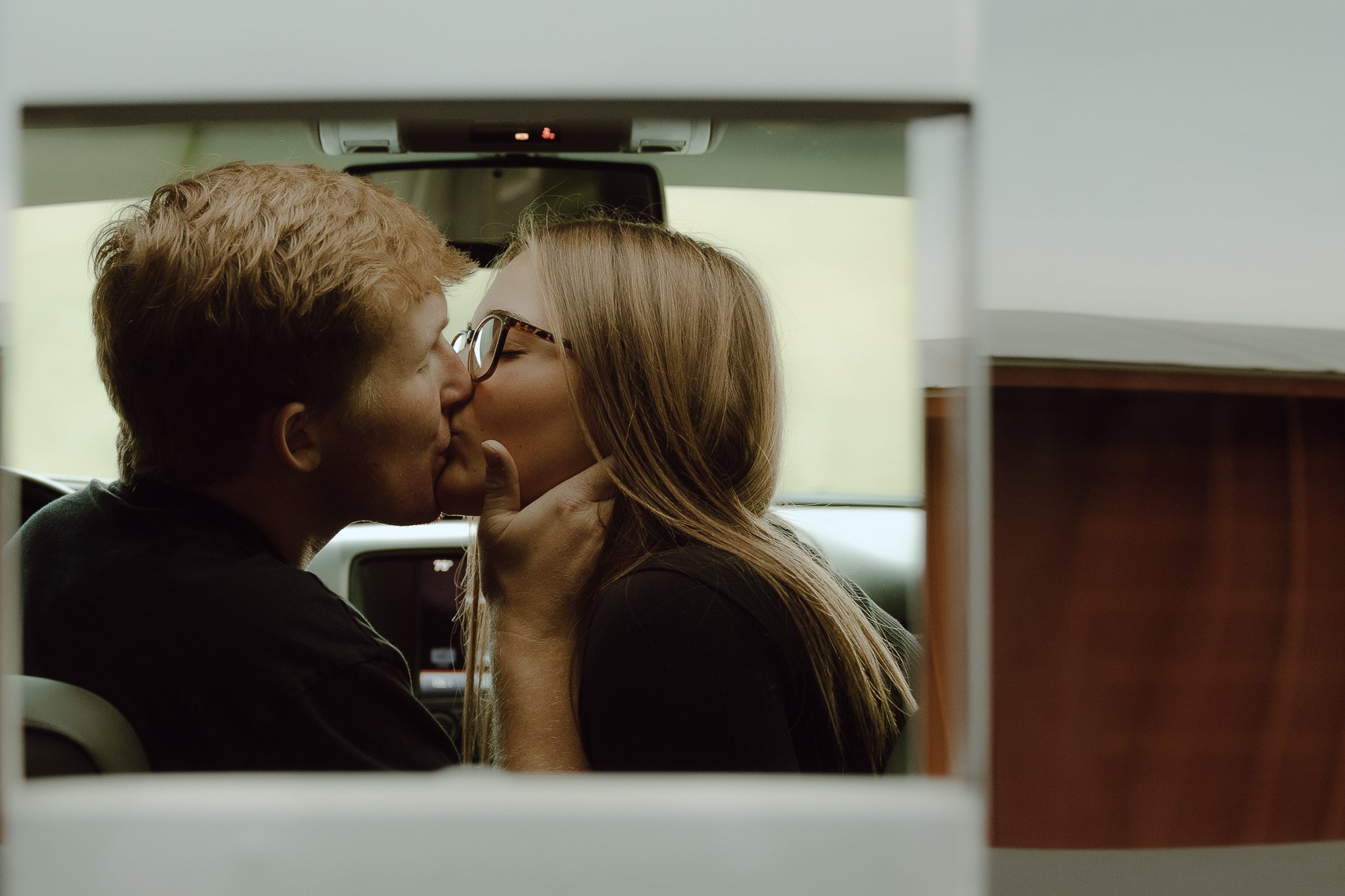 couple kissing while man grabs woman's face in a truck