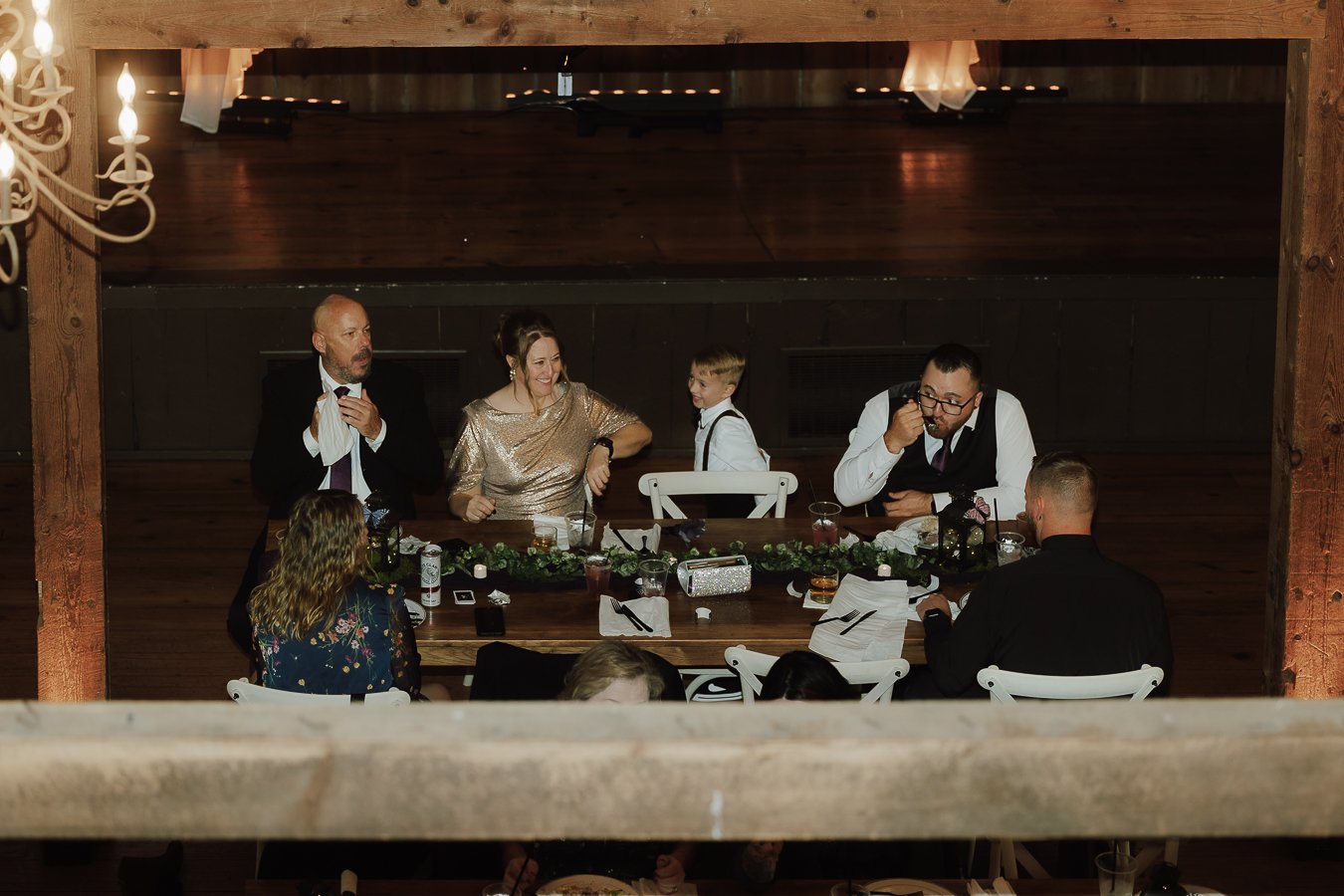 A group of seven people sitting and standing around a dining table, celebrating at a formal event.