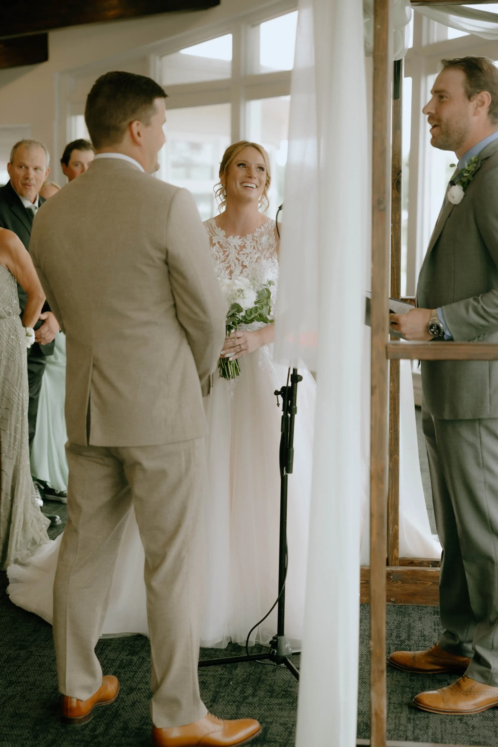 A bride and groom standing inside a wedding chapel during their vows, with guests watching in the background.