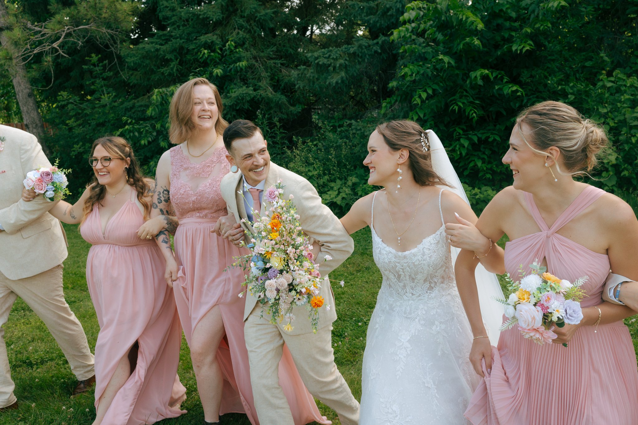 Wedding party celebrating post ceremony. People linking arms and smiling.
