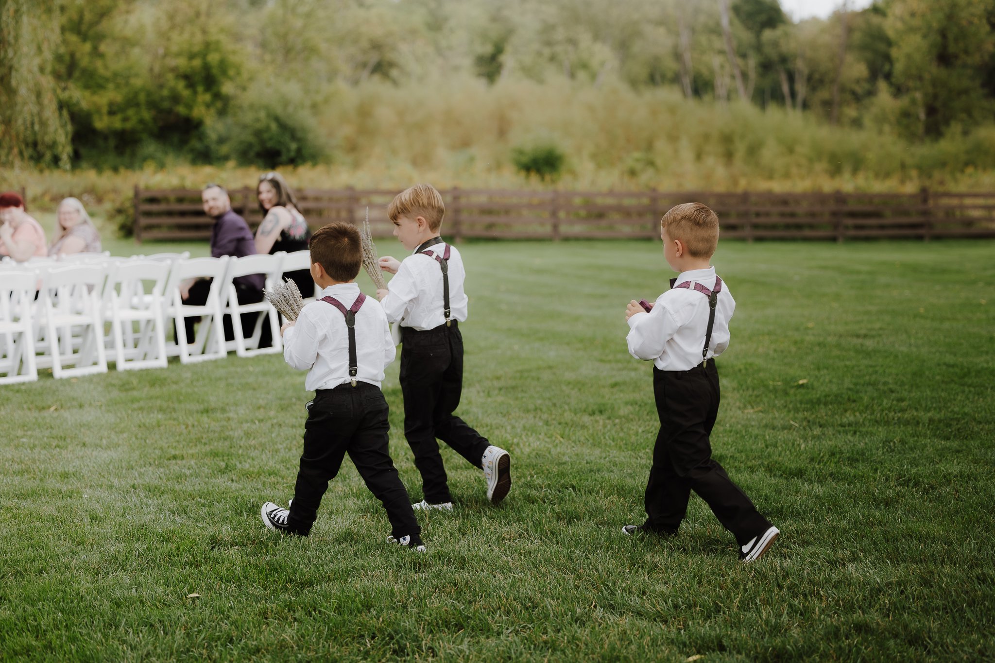 three little boys act as the ring bearers while holing lavender bouquets