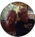A blurred image of two people sitting indoors, smiling at the camera.