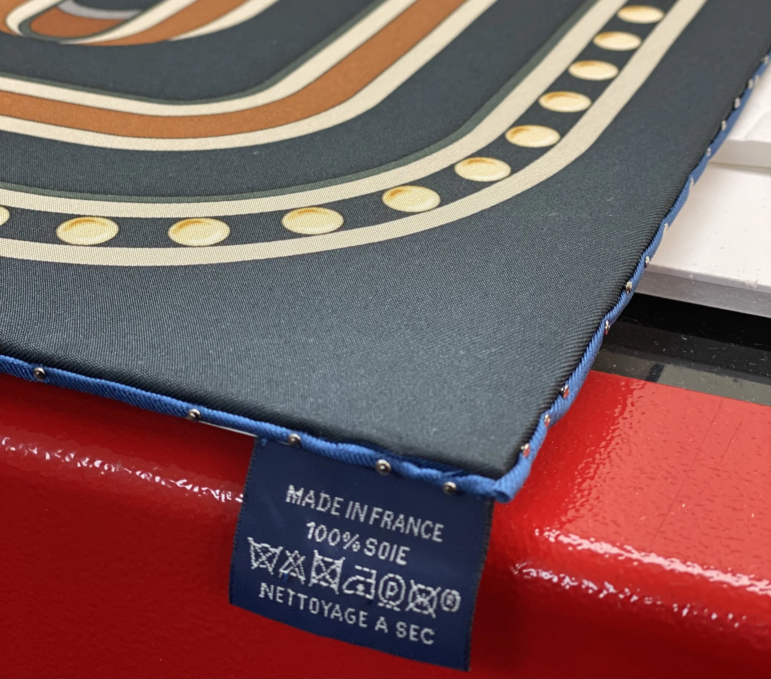 Blue fabric label with "Made in France" text on patterned silk material.
