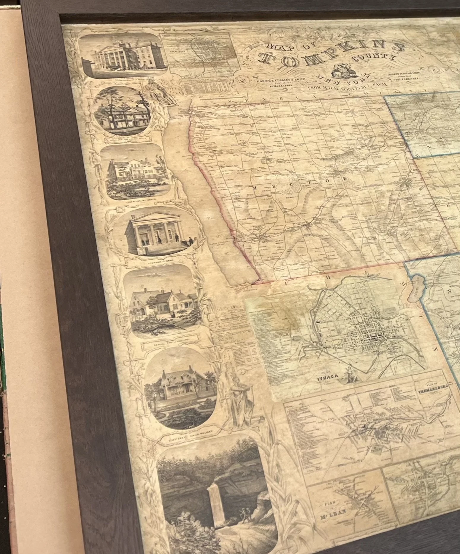 Framed antique map of Tompkins County, featuring detailed illustrations of buildings and landmarks along the border.
