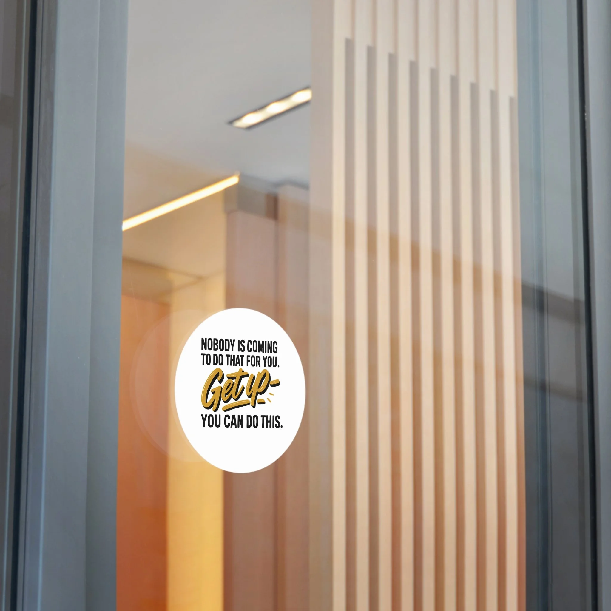 Round matte vinyl sticker with hand-lettered gold “Get up” and bold black type, motivational design for laptops and water bottles.