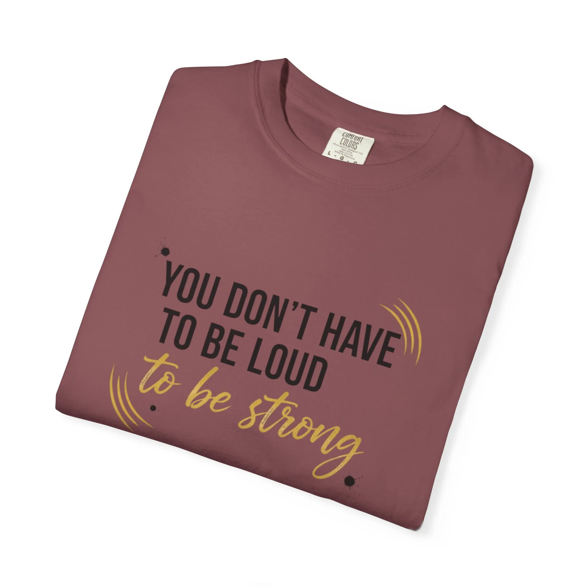 Folded T-shirt showing 'You Don’t Have to Be Loud to Be Strong' design.