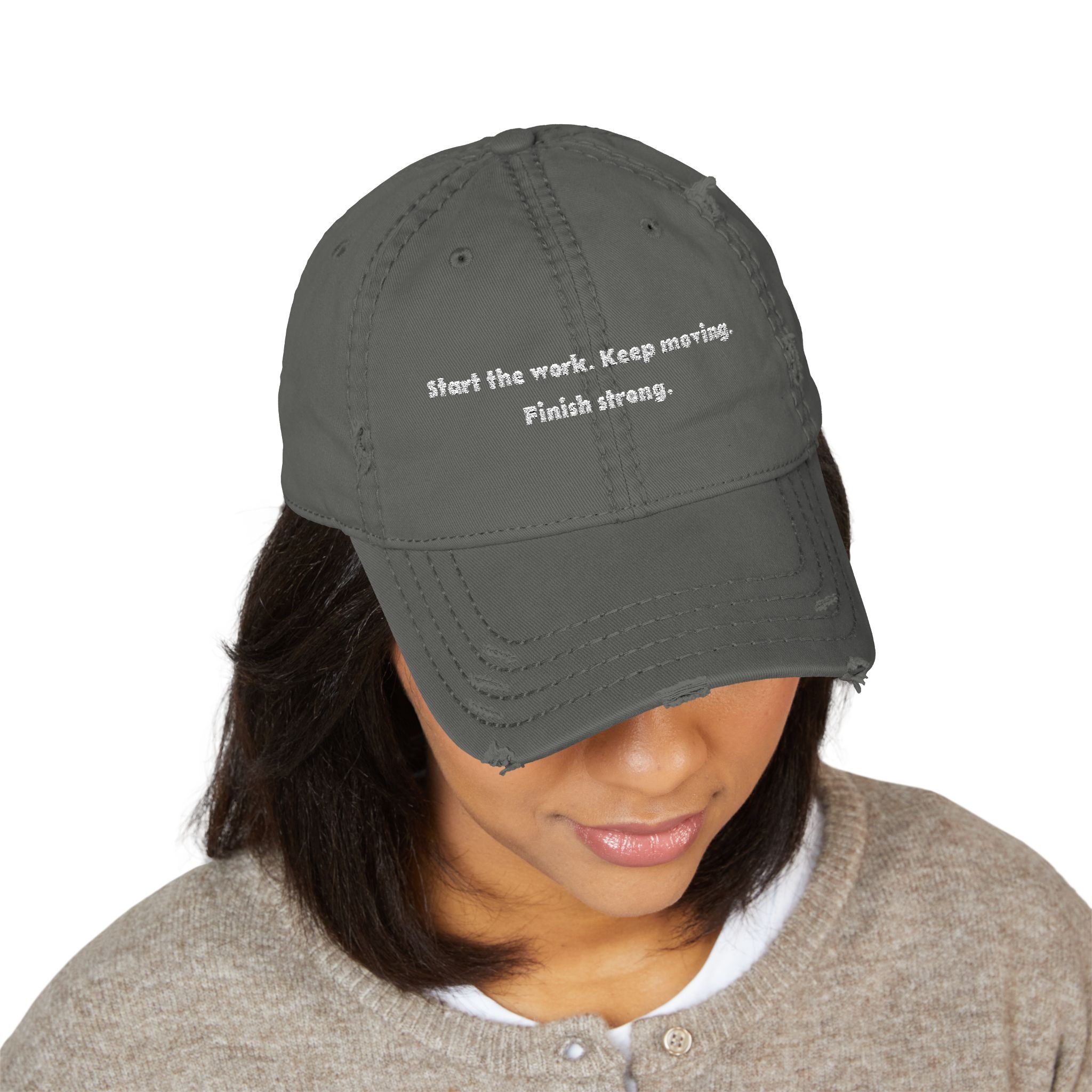 Lifestyle front view of person wearing distressed dad hat embroidered with “Start the Work. Keep Moving. Finish Strong.”