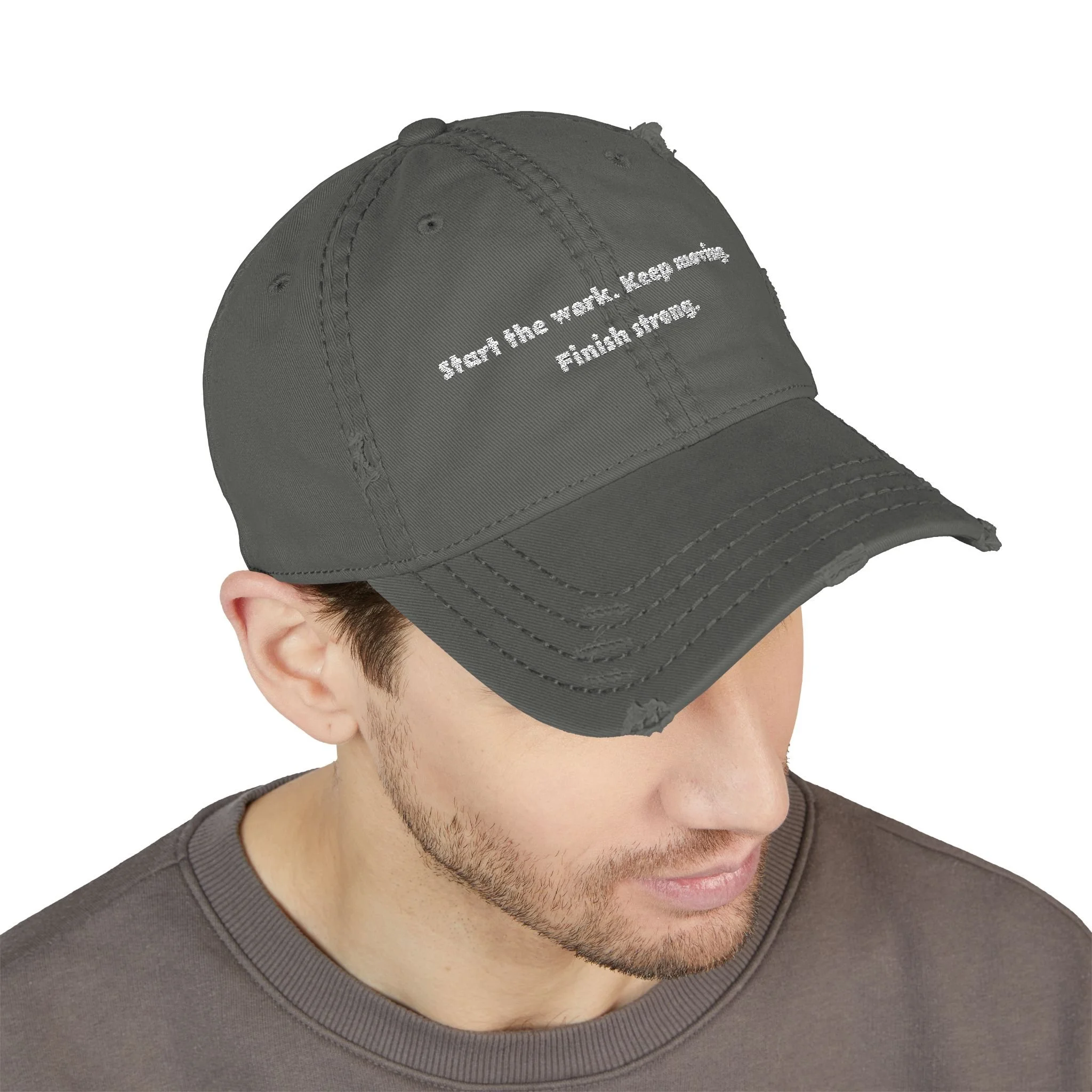 Lifestyle front view of person wearing distressed dad hat embroidered with “Start the Work. Keep Moving. Finish Strong.”