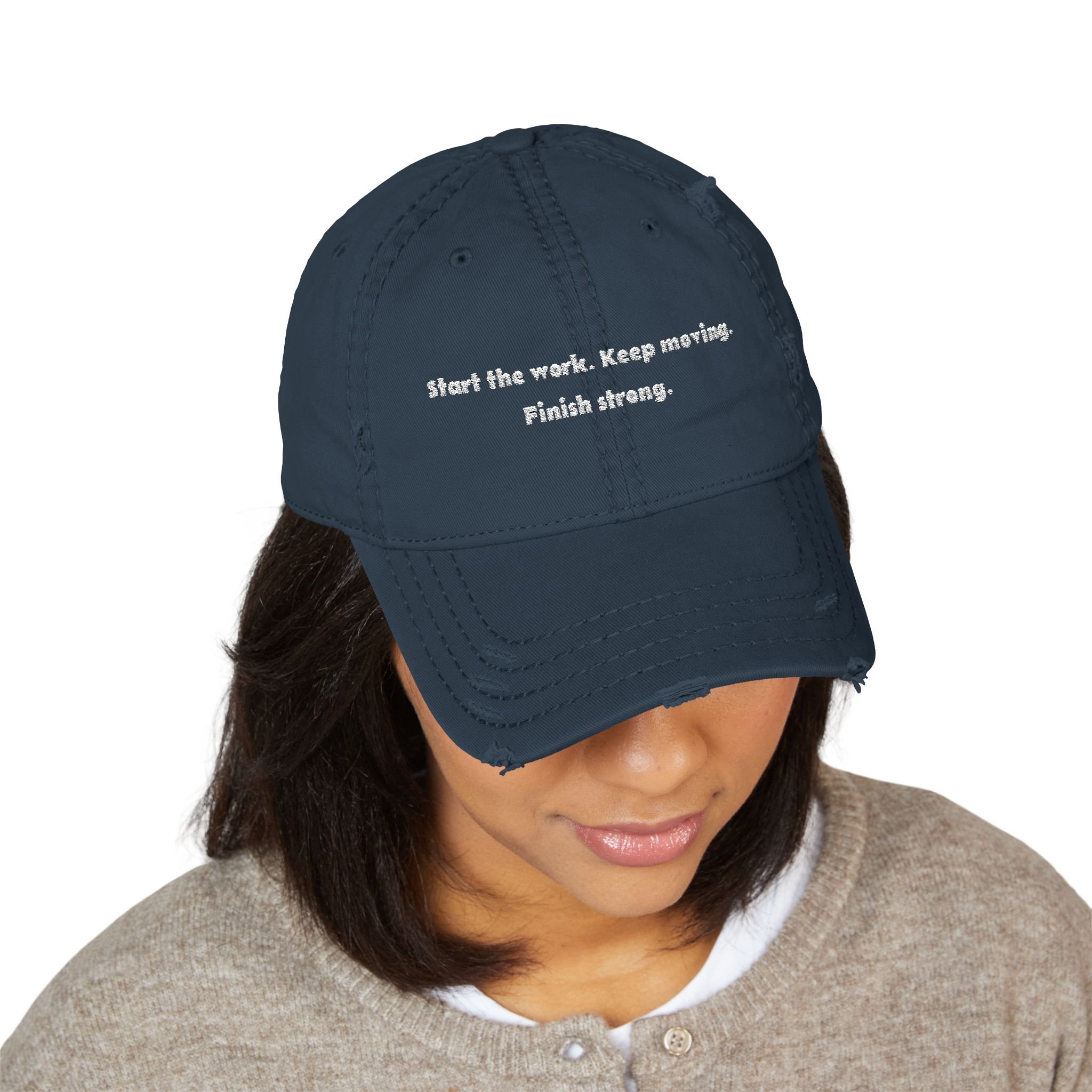 Lifestyle front view of person wearing distressed dad hat embroidered with “Start the Work. Keep Moving. Finish Strong.”