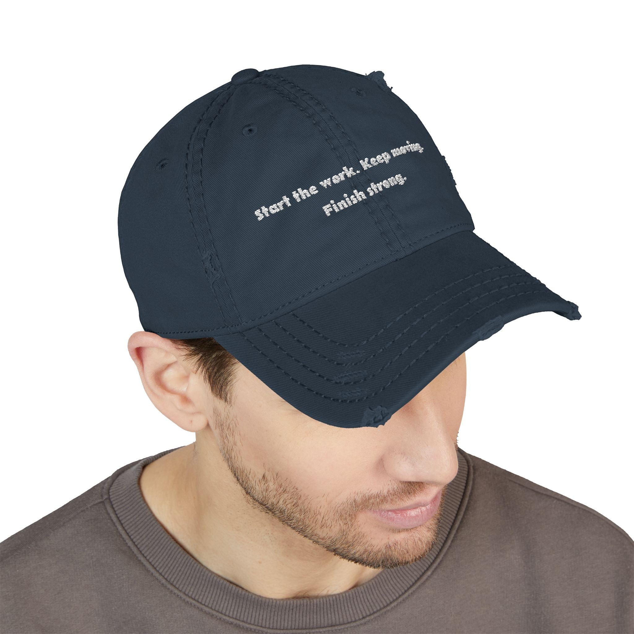 Lifestyle front view of person wearing distressed dad hat embroidered with “Start the Work. Keep Moving. Finish Strong.”