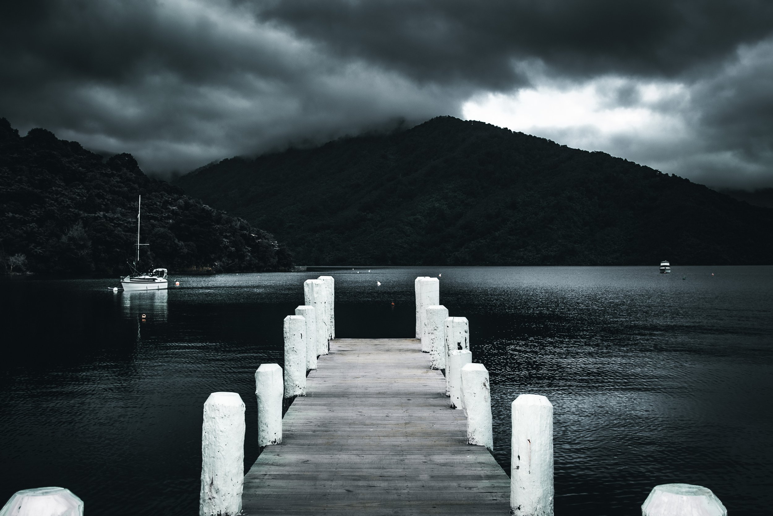 The sky darkened as the storm clouds rolled in, but the calm waters remained undisturbed. The empty dock stretched out toward the anchored boats, inviting anyone willing to brave the storm to watch as nature’s power slowly moved across the horizon