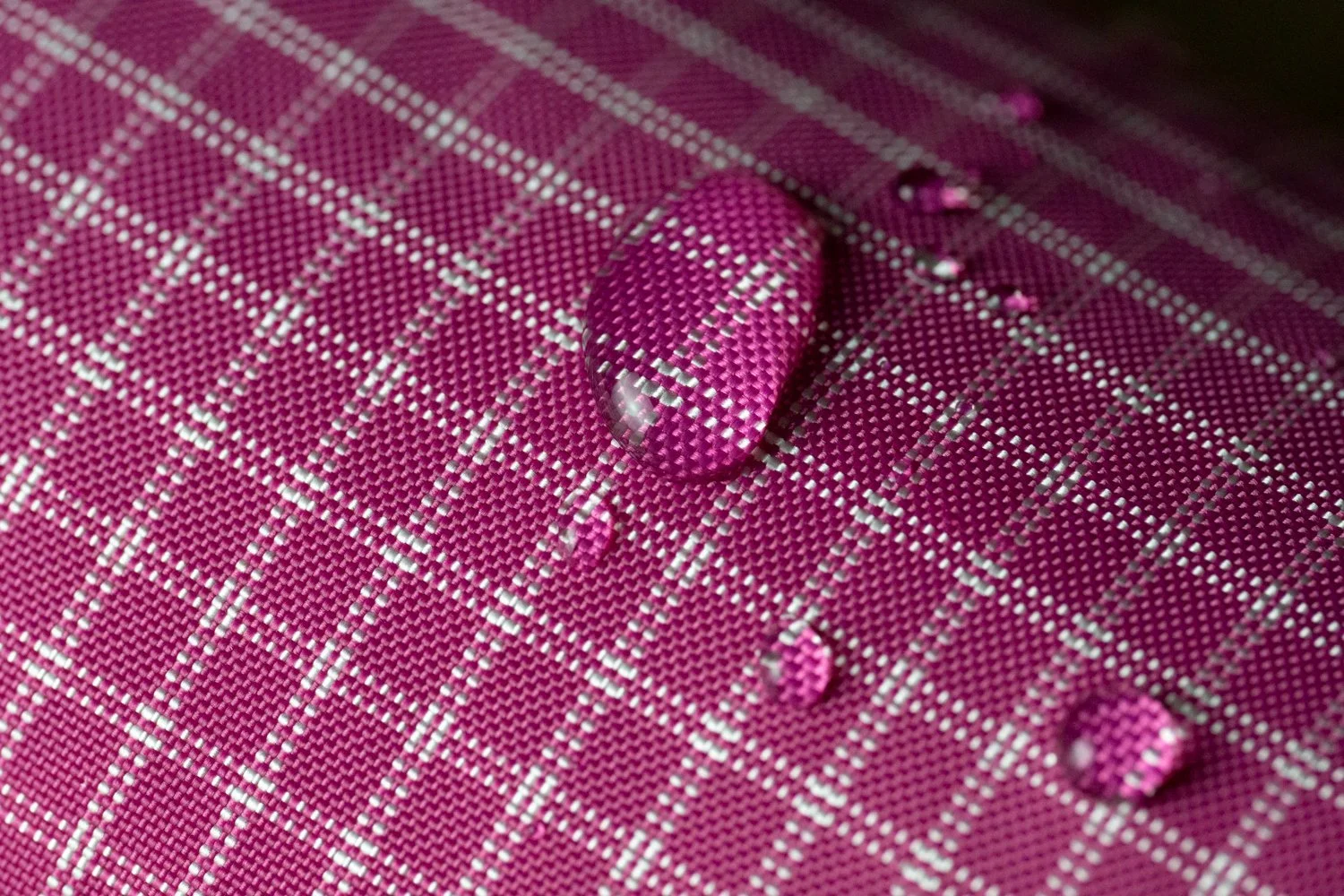 Goutte d'eau sur un tissu rose à carreaux blancs.